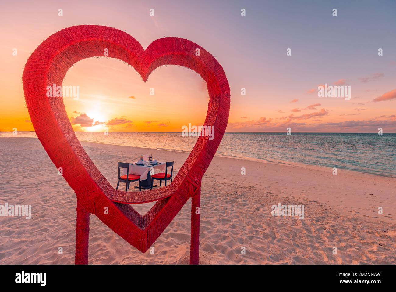 Flitterwochen-Paare-Abendessen bei einem privaten romantischen luxuriösen Abendessen am tropischen Strand auf den Malediven. Meerblick, herrliche Inselküste mit rotem Herzen Stockfoto