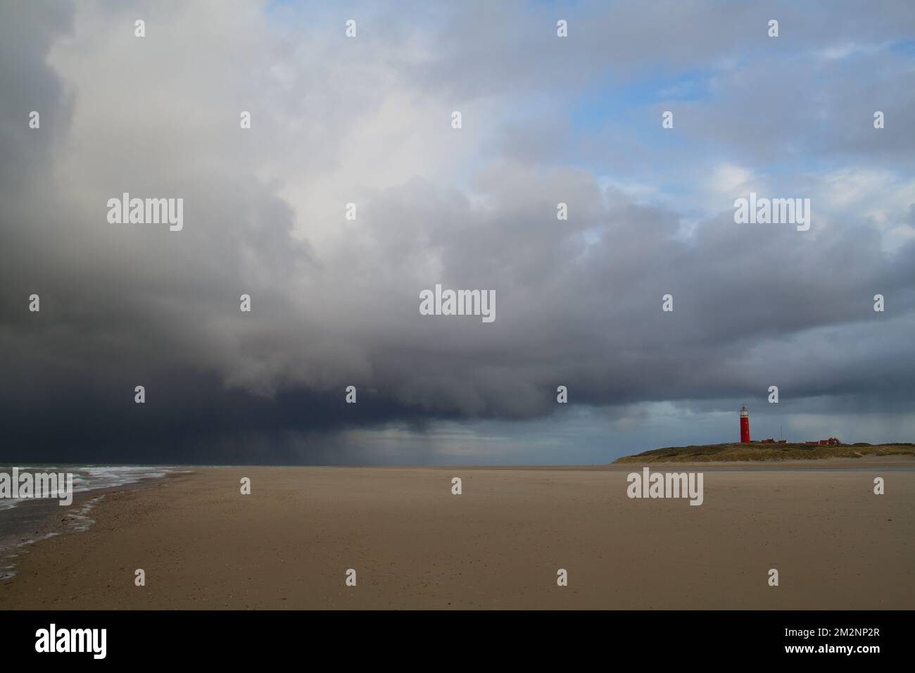 Leuchtturm, Regenwolken und breiter Strand Stockfoto