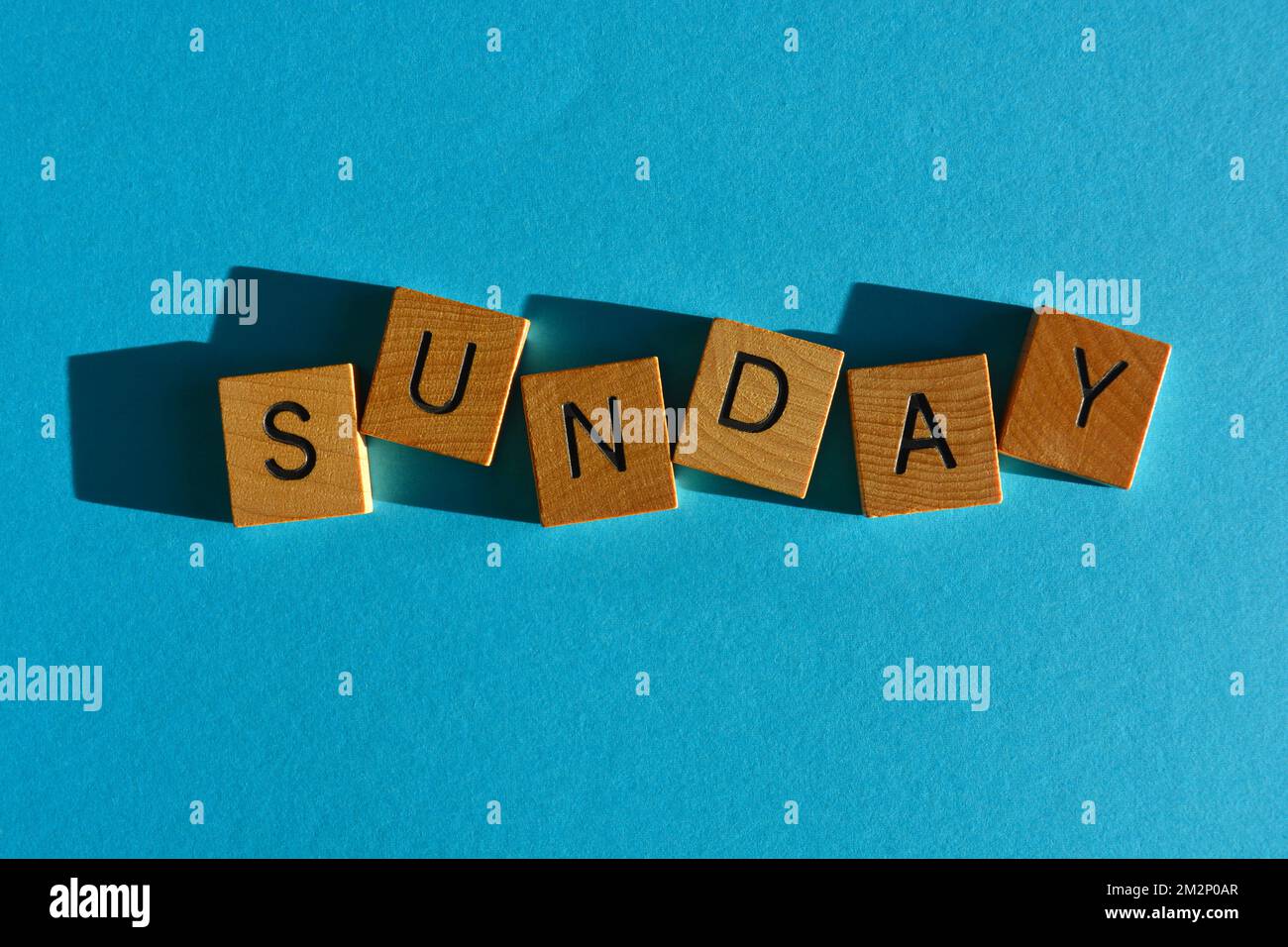 Sonntag, Wort in hölzernen Buchstaben isoliert auf hellblauem Hintergrund Stockfoto