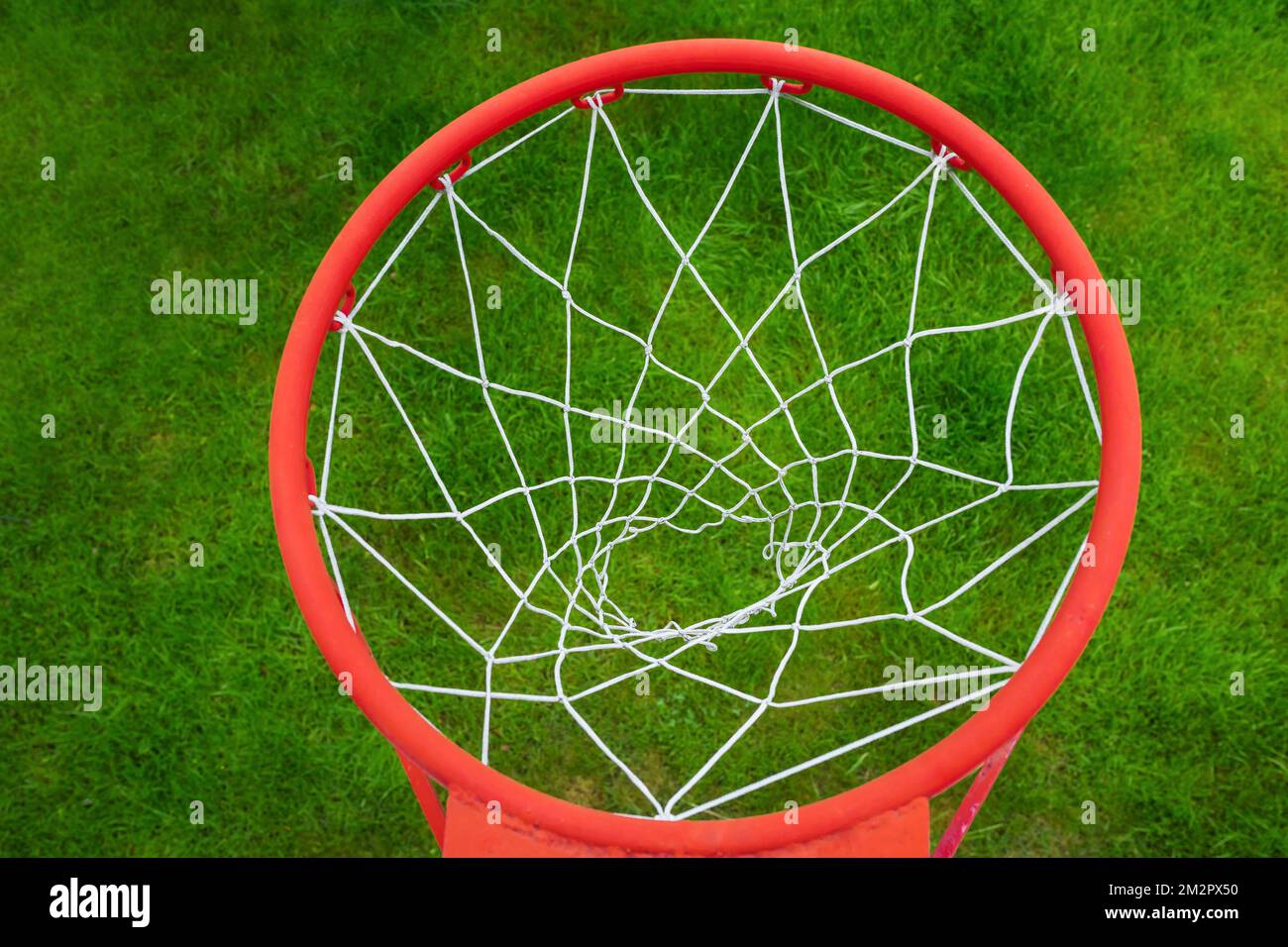 Ein roter Basketballring am Hintergrund des dicken grünen Grases. Eine Aussicht von oben Stockfoto