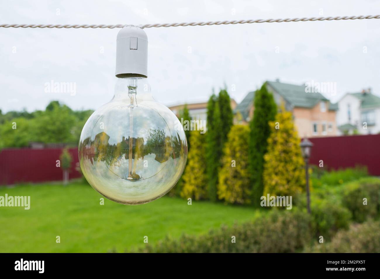 Nahaufnahme einer Glühlampe, die tagsüber auf der Straße im Garten hängt Stockfoto