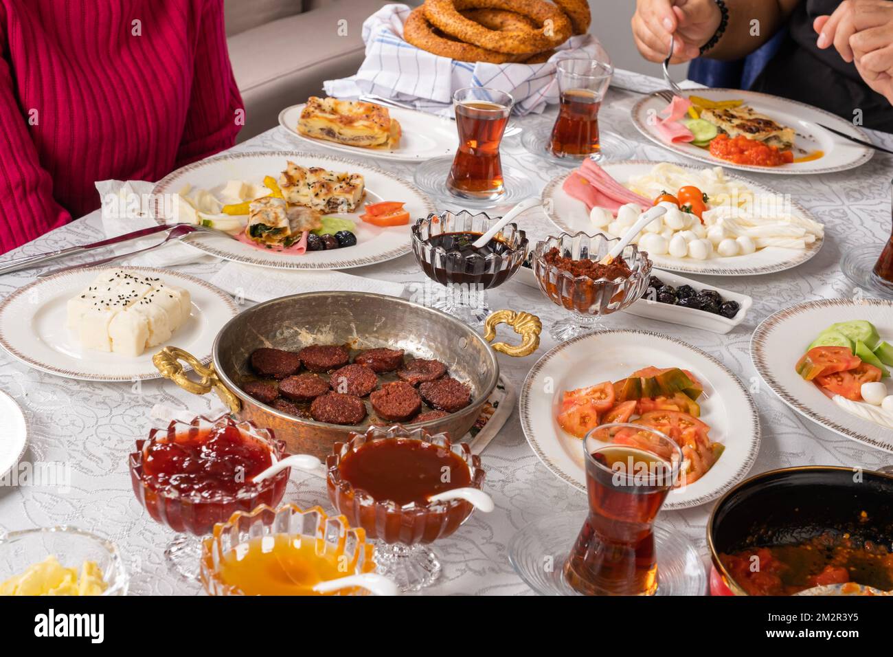 Morgenroutine mit glücklichem Familienfrühstück. Traditionelle, leckere, moderne türkische Küche. SIMIT, Bagel, Sucuk, Wurst, Käse, Tee im Glas, Tomaten. Stockfoto