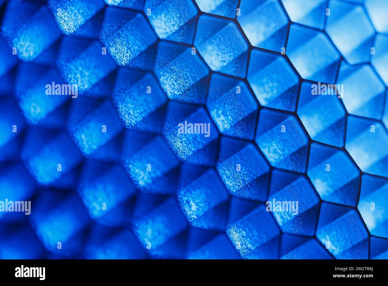 Abstrakter geometrischer Hintergrund von sechseckigen Zellen mit blauen Hervorhebungen und geringer Schärfentiefe Stockfoto