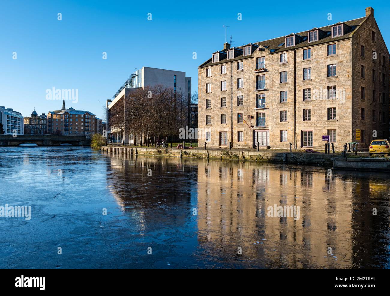 Leith, Edinburgh, Schottland, Großbritannien, 14.. Dezember 2022. UK Weather: Das Wasser des Leith River ist gefroren: Die anhaltenden Gefrierbedingungen haben dazu geführt, dass der Fluss an der Küste gefriert und so farbenfrohe Reflexionen eines umgebauten Anleihegeländes, heute Wohnungen, im Eis erzeugt. Kredit: Sally Anderson/Alamy Live News Stockfoto