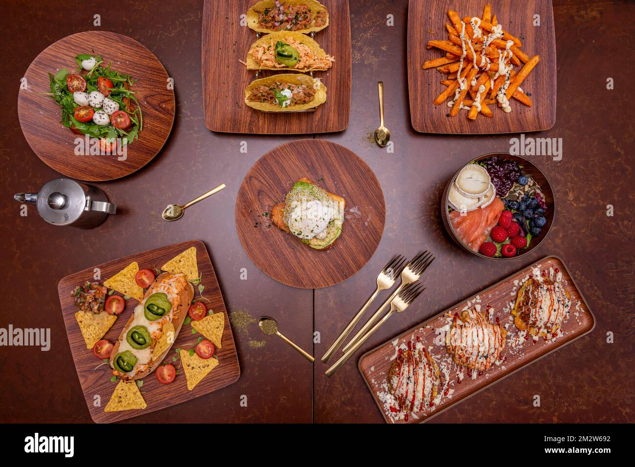 Köstliche internationale Speisenrezepte, mit einer Schüssel Lachs und rotem Obst, einem mexikanischen Hotdog, gefüllten Tacos, Patacones mit Käse und Salat mit moz Stockfoto