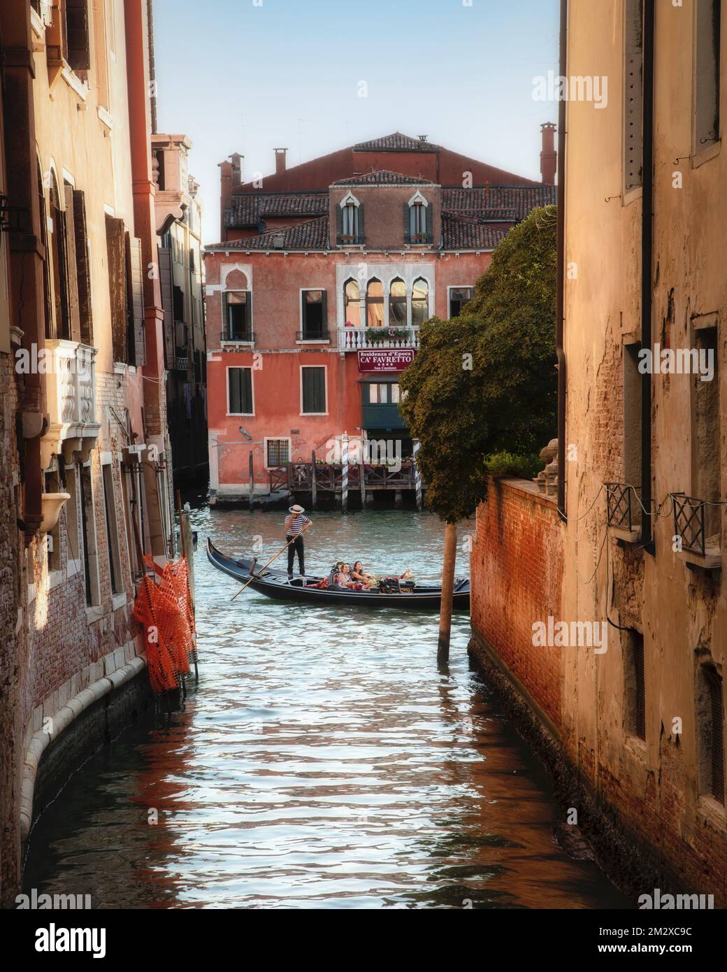 Ein flüchtiger Blick auf eine Gondel, die sich langsam entlang des Canal Grande bewegt, vorbei an einem der vielen Seitenkanäle im historischen Venedig, Italien. Stockfoto