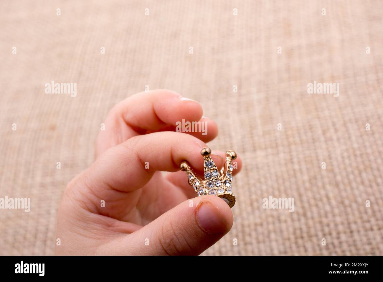 Hand hält eine kleine Modell-Krone in der hand Stockfoto