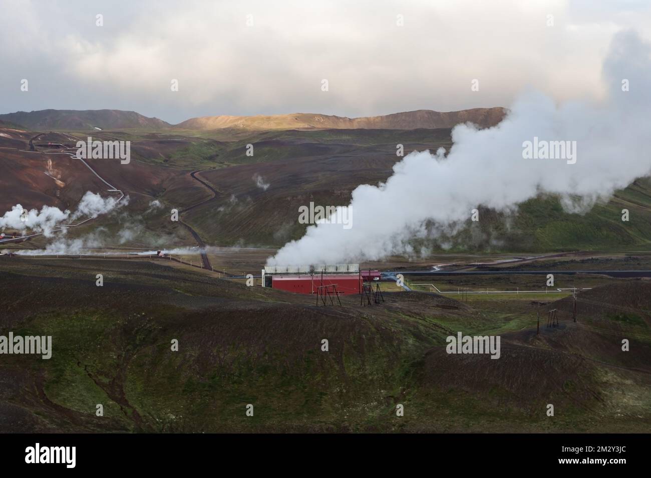 Das geothermische Kraftwerk Krafla wird dampfend betrieben. Vulkangebiet Myvatn, Island, Europa. Dampf kommt aus Rohren. Farbenfrohe, grüne und braune Hügel und Berge Stockfoto