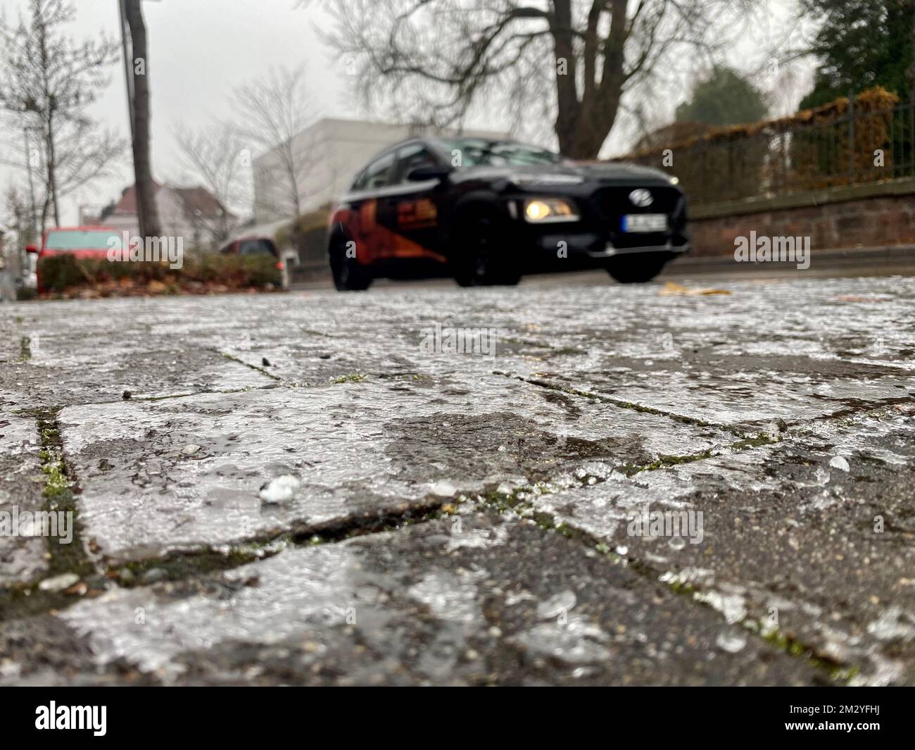 Lahr, Deutschland. 14.. Dezember 2022. Ein Auto fährt an einem eisbedeckten Bürgersteig vorbei. Aufgrund vereister Straßen gab es zahlreiche Unfälle und Einsätze von Rettungsdiensten, Feuerwehr und Polizei in Südbaden. Kredit: Mark Alexander/Badische Zeitung/dpa/Alamy Live News Stockfoto