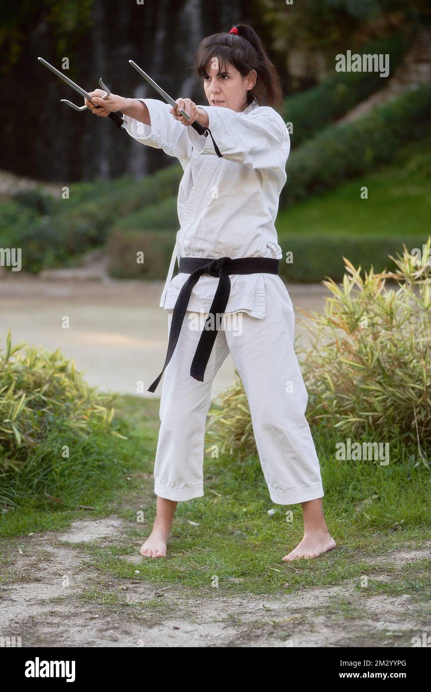 Junge Karate-Frau in Kampfposition hält ein Paar sai draußen. Hochwertiges Foto Stockfoto