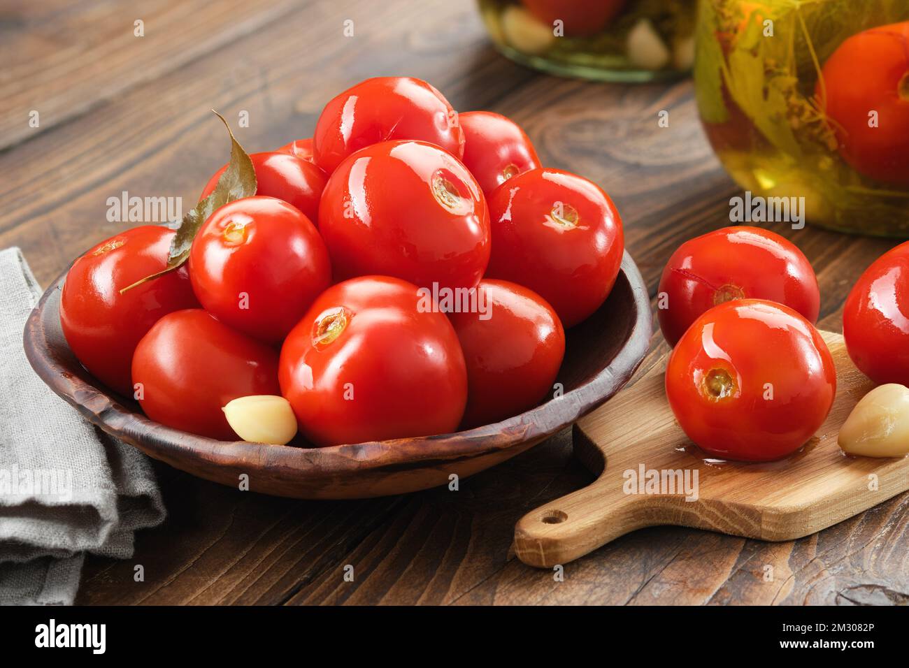 Hausgemachte eingelegte Tomaten. Schüssel mit Tomatenkonserven. Mariniertes Gemüse in Glasgefäßen im Hintergrund. Stockfoto