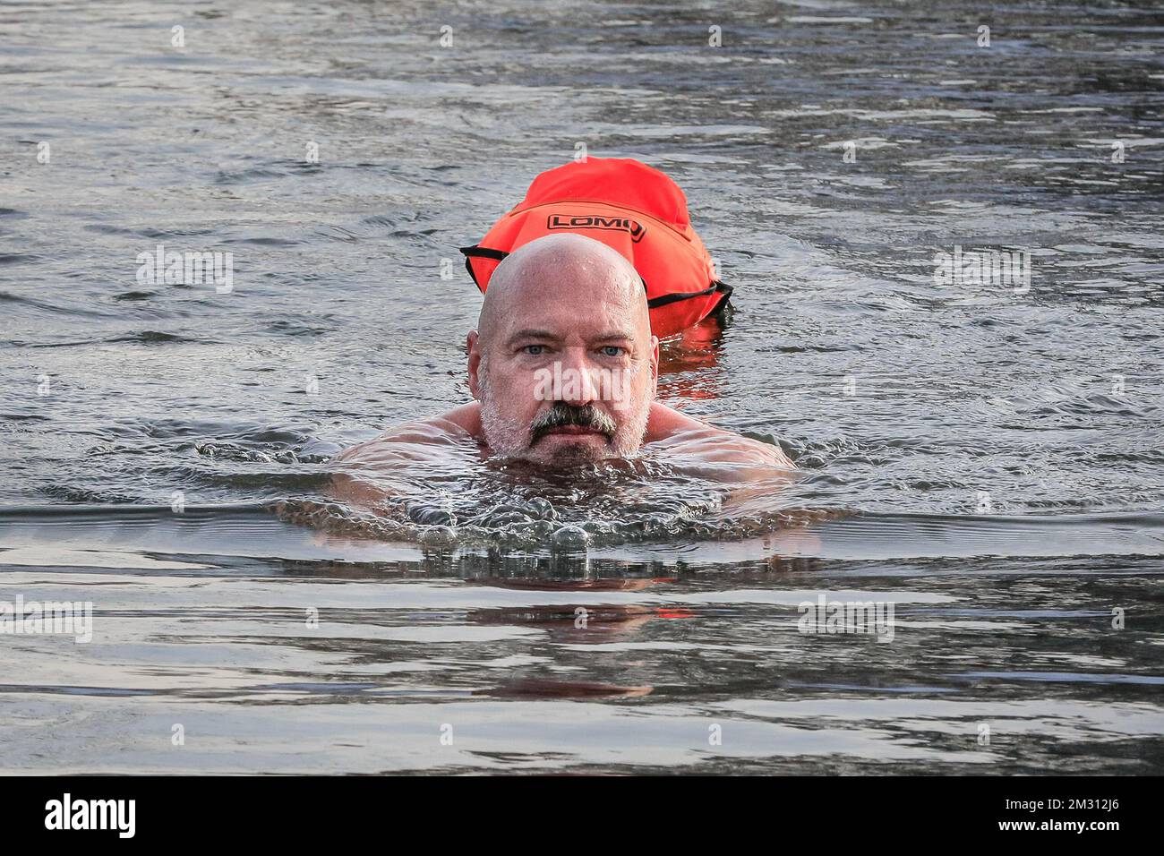 London, Großbritannien. 14.. Dezember 2022. Schwimmer Bernd ist gekommen, um zu schwimmen und erstickt das Wasser mit einem Lächeln. Schwimmer trotzen dem kalten, aber sonnigen Wetter und schwimmen im offenen Wasser im Beckenham Place Park Swimming Lake, einem See in natürlicher Umgebung im Beckenham Place Park im Südosten Londons. Zwei voll ausgebildete Rettungsschwimmer sind anwesend mit Rettungsausrüstung für die gebuchten Schwimmgänge im offenen Wasser und alle Schwimmer hatten Einführungssitzungen zum Schwimmen im Winter und Sicherheitsmaßnahmen und schwimmen mit einer Rettungsboje. Kredit: Imageplotter/Alamy Live News Stockfoto