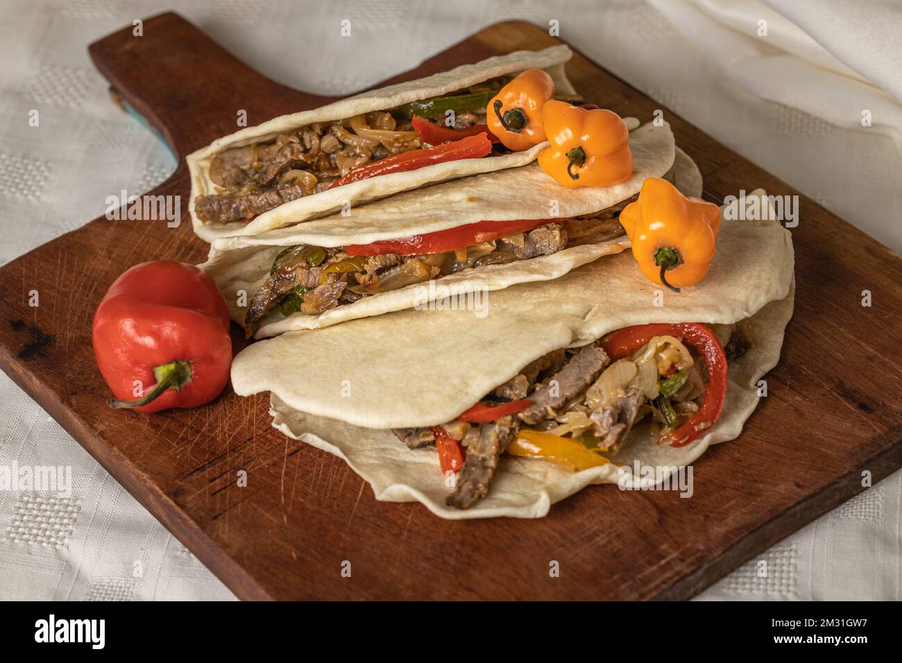 Tacos, typisch mexikanisches Essen, mit Rindfleisch, Gemüse und Chili-Pfeffer auf einem Holzbrett. Stockfoto