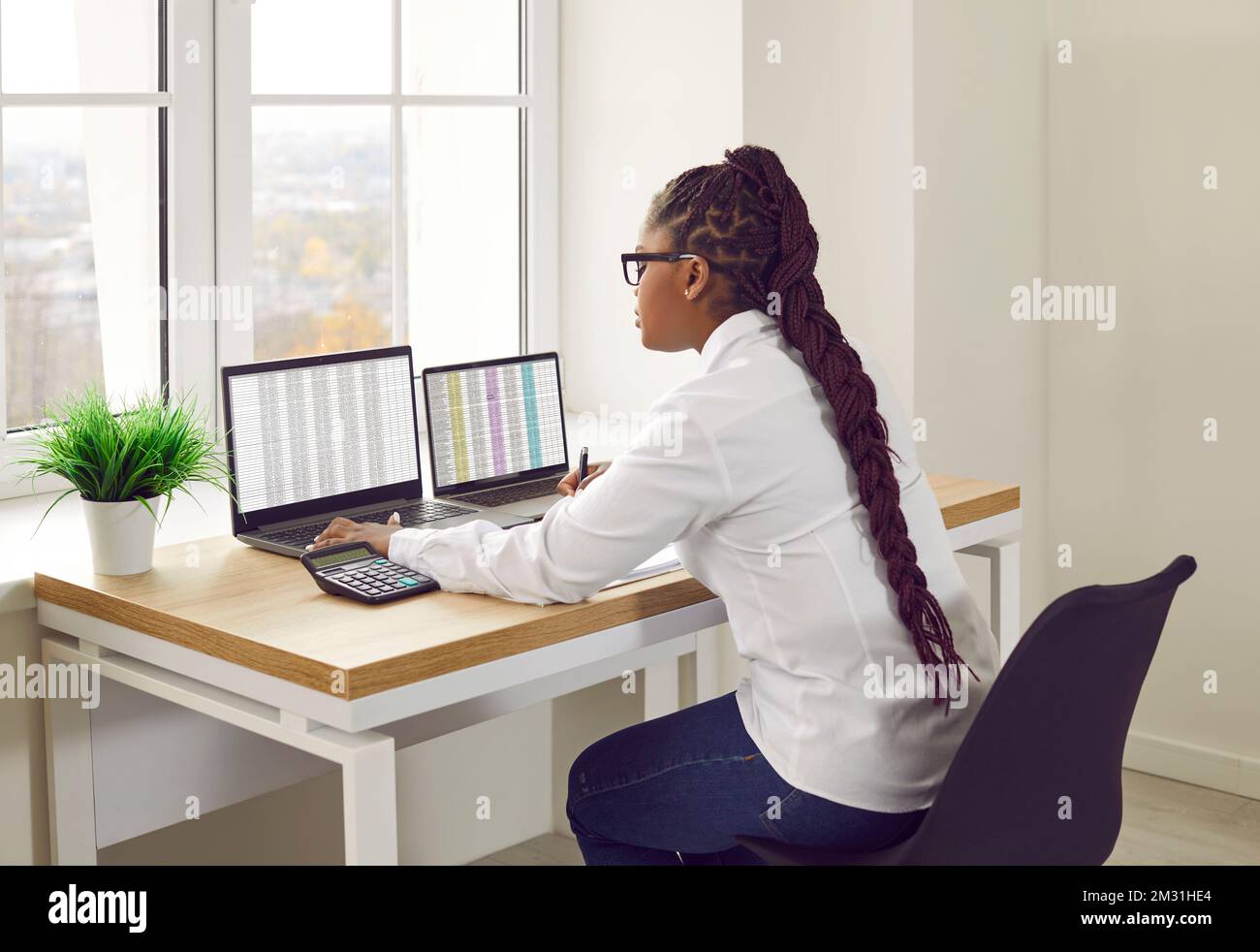 Buchhalterin, die im Büro arbeitet, an ihrem Tisch sitzt und Laptops benutzt Stockfoto