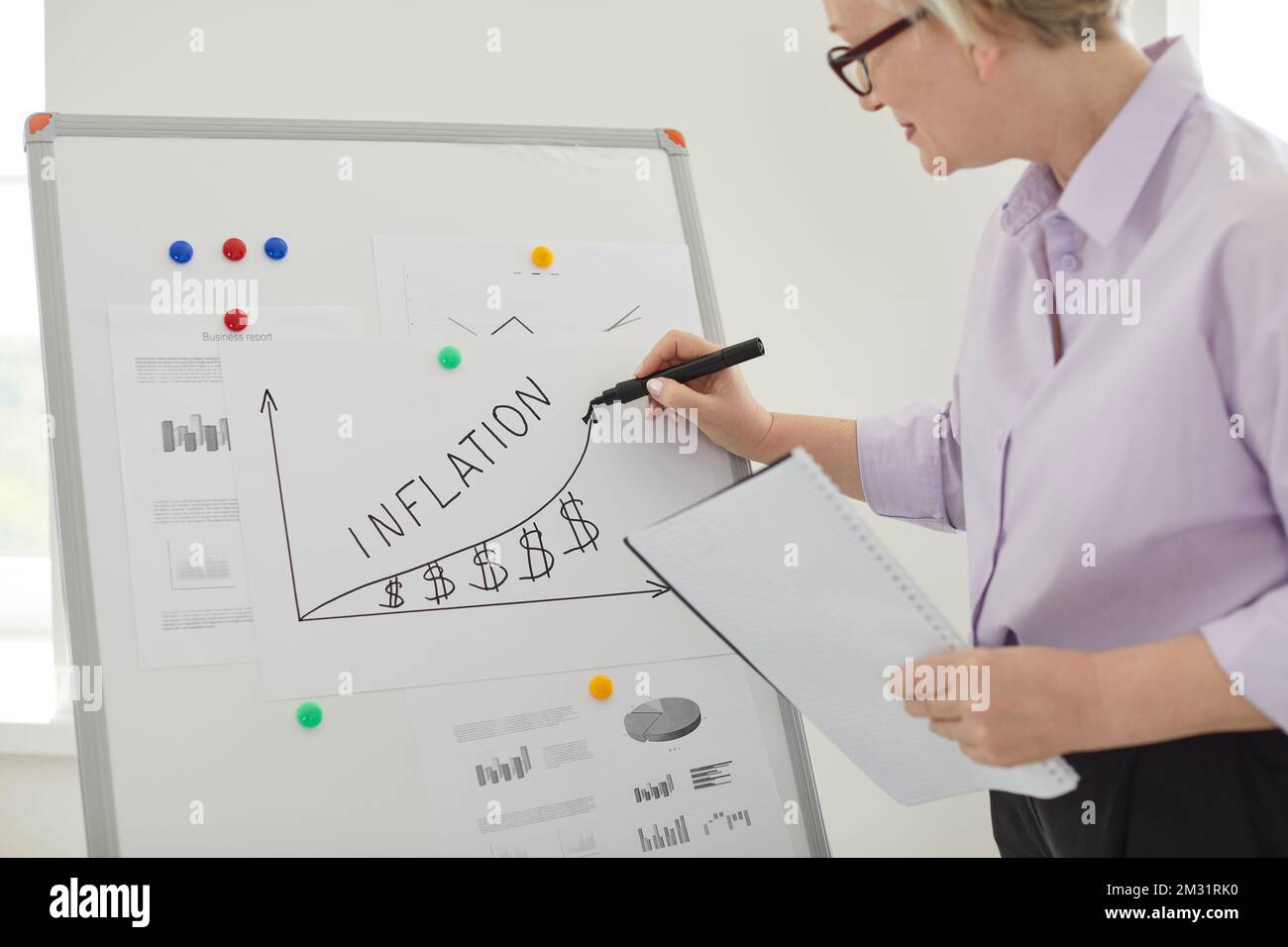 Geschäftsfrau, die eine Grafik der steigenden Inflation auf einem Whiteboard im Büro zeichnet Stockfoto