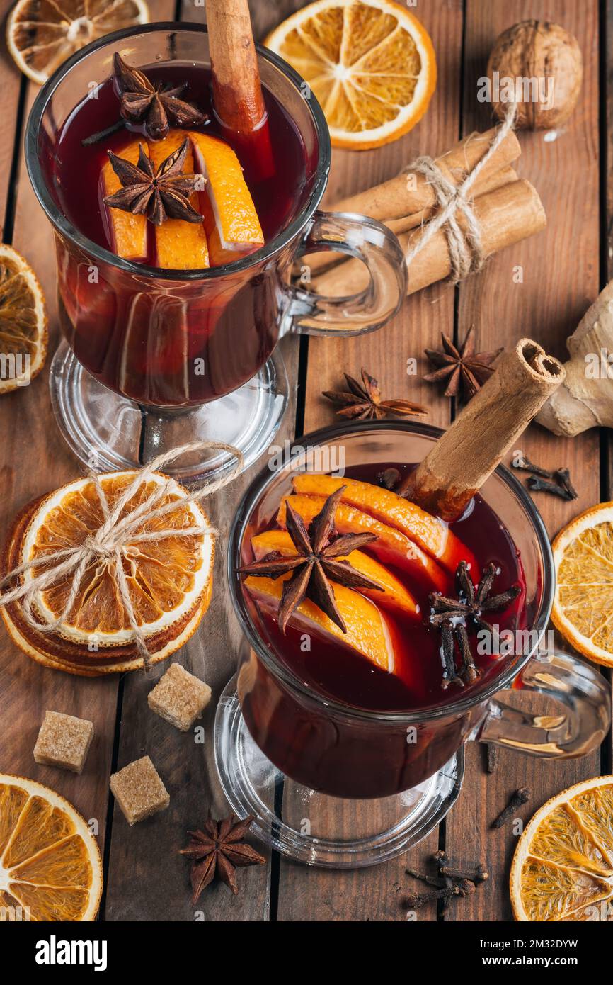 Glühwein mit Gewürzen auf einem rustikalen Holztisch. Stockfoto