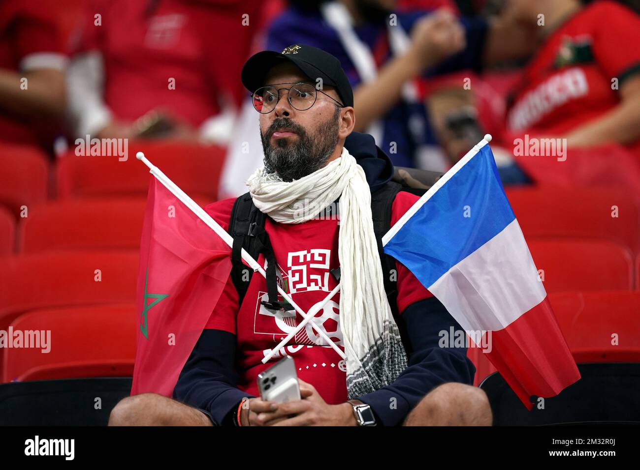 Vor dem Halbfinalspiel der FIFA-Weltmeisterschaft im Al Bayt Stadium in Al Khor, Katar, fällt ein Fan Frankreichs und Marokkos unter die Flagge. Bilddatum: Mittwoch, 14. Dezember 2022. Stockfoto