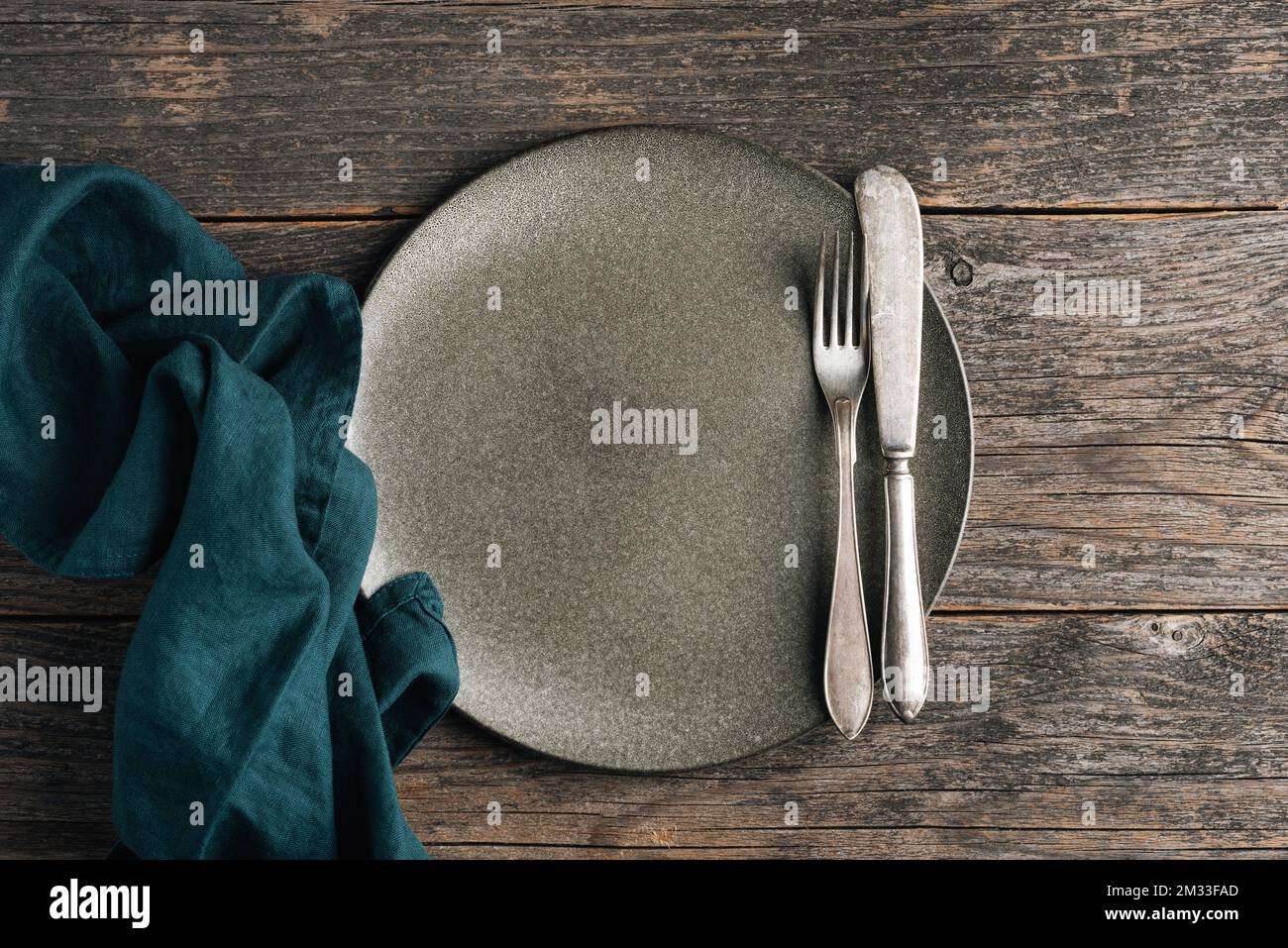 Altmodisches Besteck und leerer grüner Teller auf einem Holztisch. Esstisch. Draufsicht Stockfoto