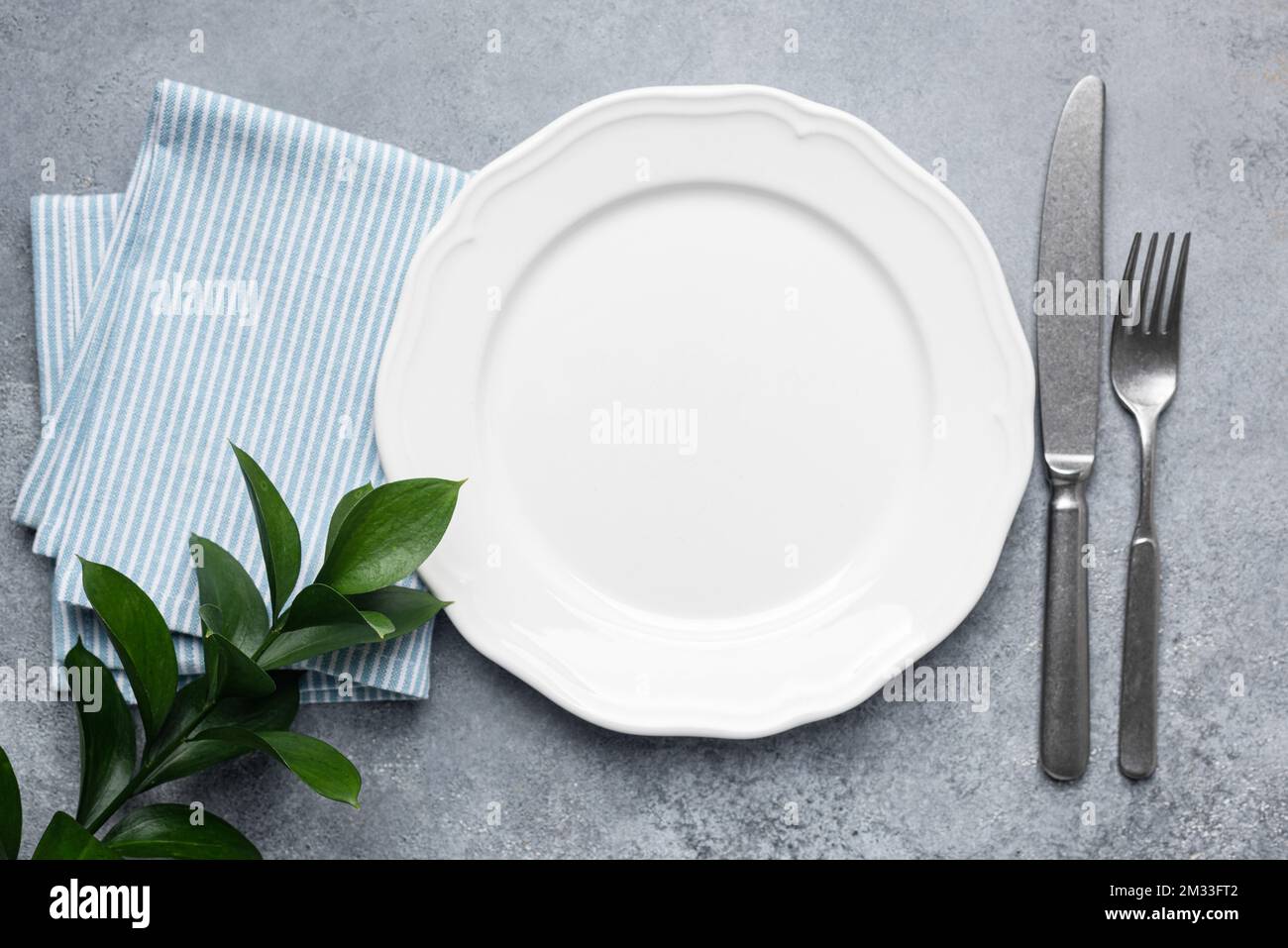 Weißer Teller mit Besteck und Serviette. Tischbestuhlung, eleganter Essteller. Draufsicht, Kopierbereich Stockfoto