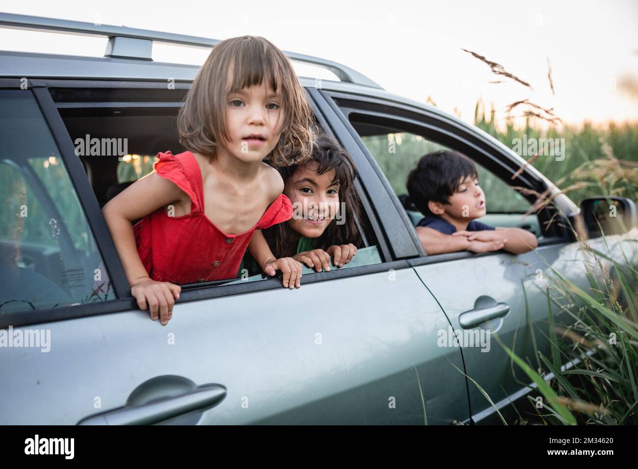 Drei Mädchen, die von den Autofenstern der Familie aus zusehen Stockfoto