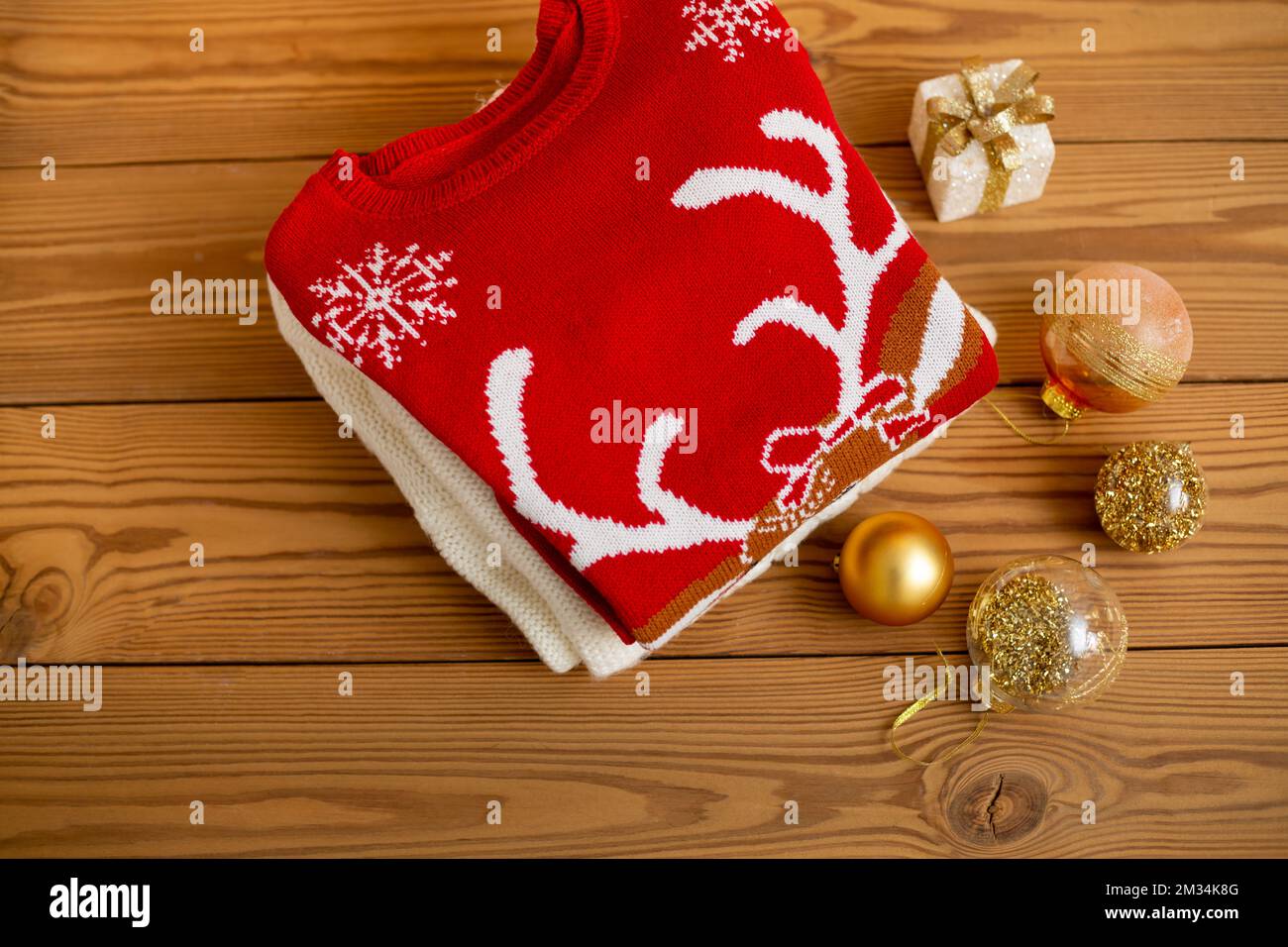 Warme Weihnachtspullover. Winterurlaub Strickpullover mit Muster auf Holzhintergrund und Weihnachtsdekorationen. Ein Haufen warmer Weihnachten Stockfoto