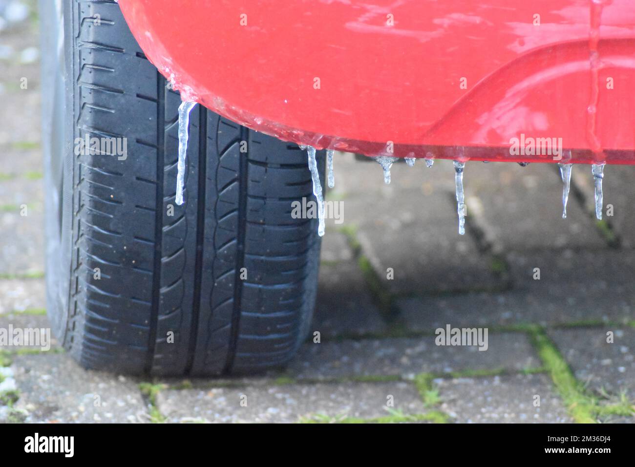 Eiszapfen am hinteren Stoßfänger eines roten Autos. Stockfoto