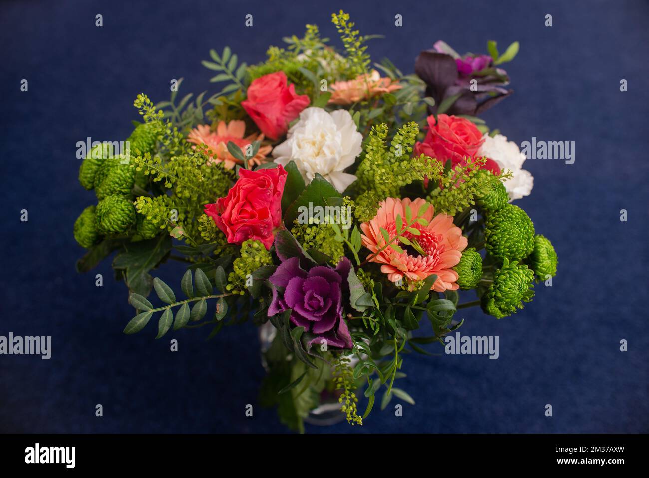 Blumenstrauß aus roten Gerberas, Nelken und Grün in einer Glasvase, professionell hergestellt Stockfoto