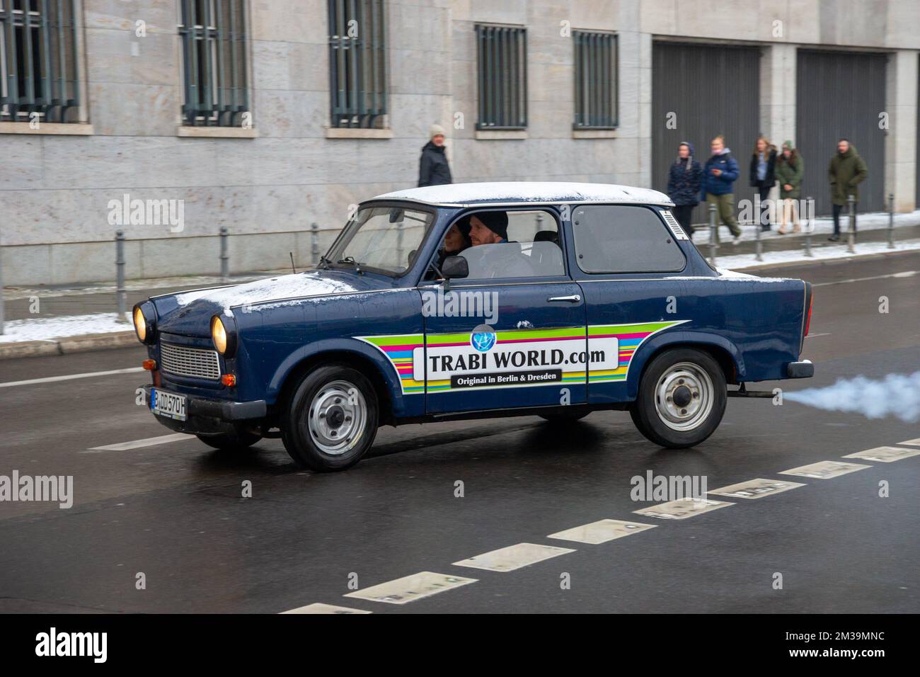 Ein Trabant-Auto aus Berlins Trabi World fährt vorbei. Rauchige Emissionen sind am Auspuffrohr des Fahrzeugs zu erkennen Stockfoto