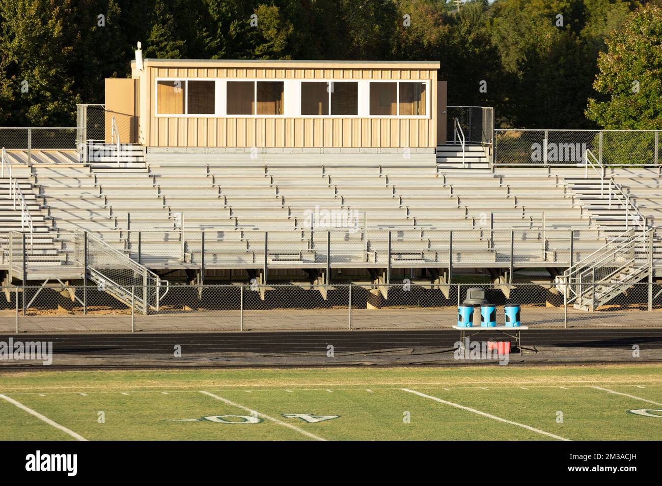 An einem Herbstabend kurz vor Sonnenuntergang gibt es ein normales Metall-Highschool-American-Football-Stadion mit Presseboxen und ein Publikum aus Metall mit Tribünen. Stockfoto