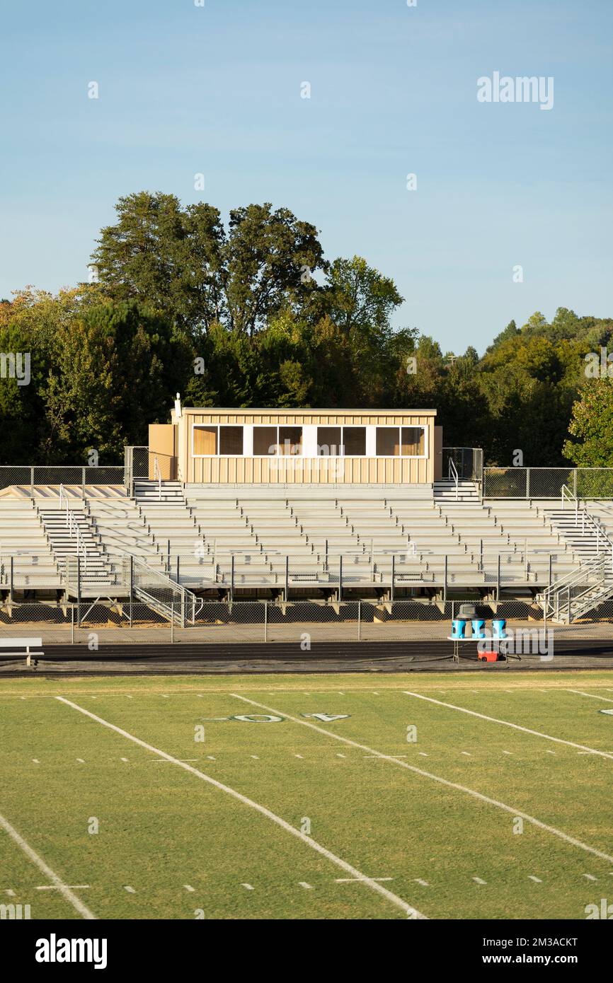 An einem frühen Herbstabend kurz vor Sonnenuntergang gibt es ein normales Metall-Highschool-American-Football-Stadion mit Presseboxen und ein Publikum aus Metall mit Tribünen. Stockfoto