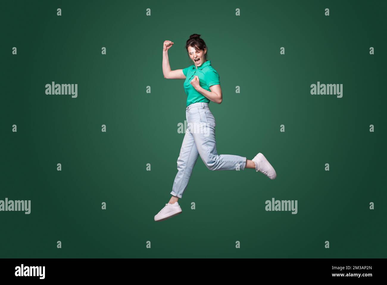 Full size profile photo of brunette lady running celebrating favorite team victory isolated on green background. Happiness, win, success. Full length. Stockfoto