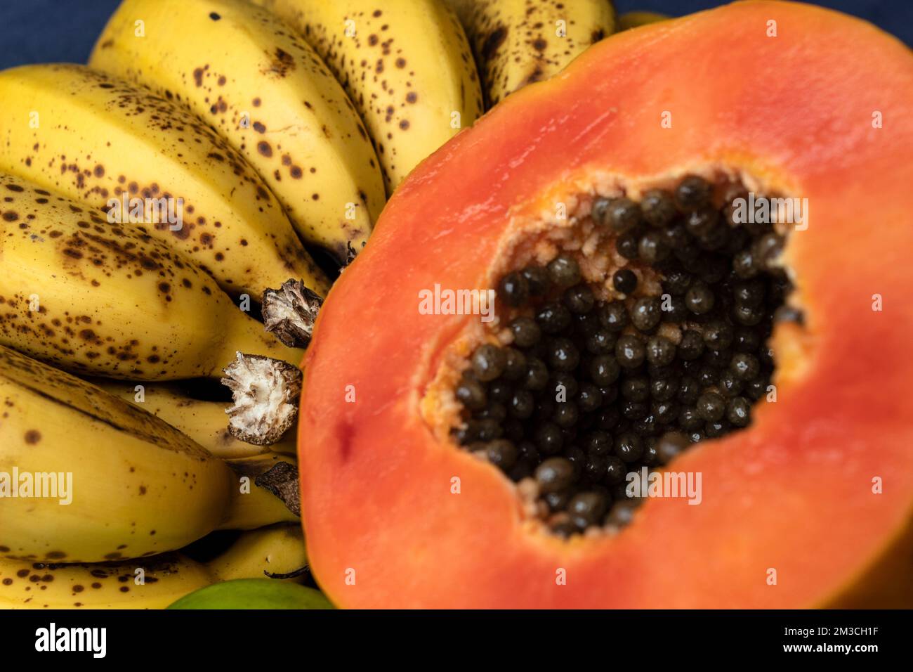 Aus nächster Nähe sehen Sie eine frisch geschnittene Orangenpapaya mit Samen im Inneren, Sommersprossen und Zitronen im Hintergrund. Obst- und Esskonzeptsfotografie Stockfoto