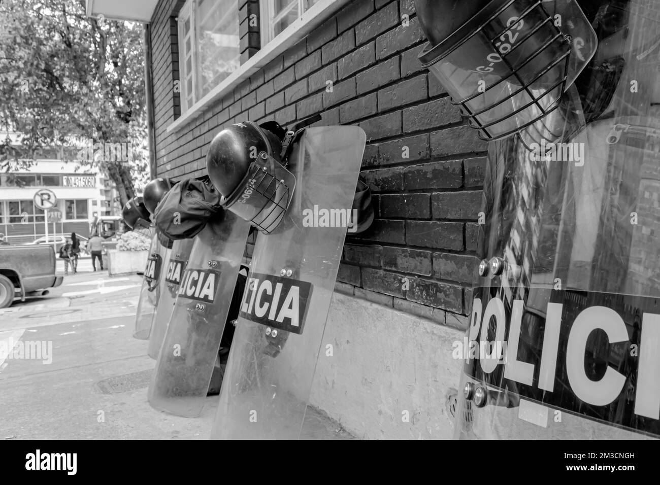 Polizeihelme und Schutzschilde über einer dunkelroten Mauer, die auf Störungen warten Stockfoto
