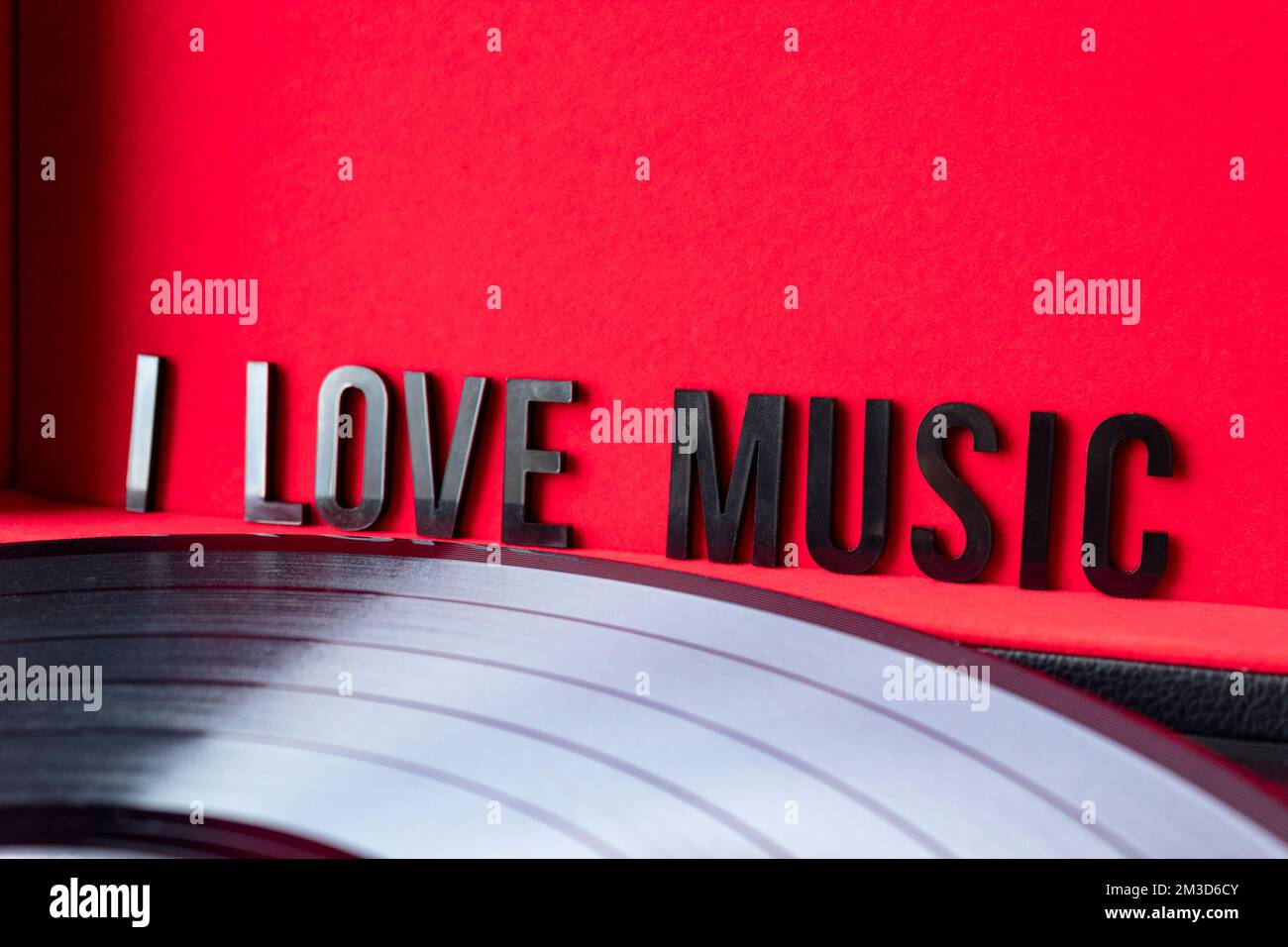 Nahaufnahme eines „I love“-Schriftzugs auf rotem Hintergrund mit lp-Vinyl auf dem Plattenspieler. Konzept für Musikliebhaber. Langzeitbelichtung Stockfoto