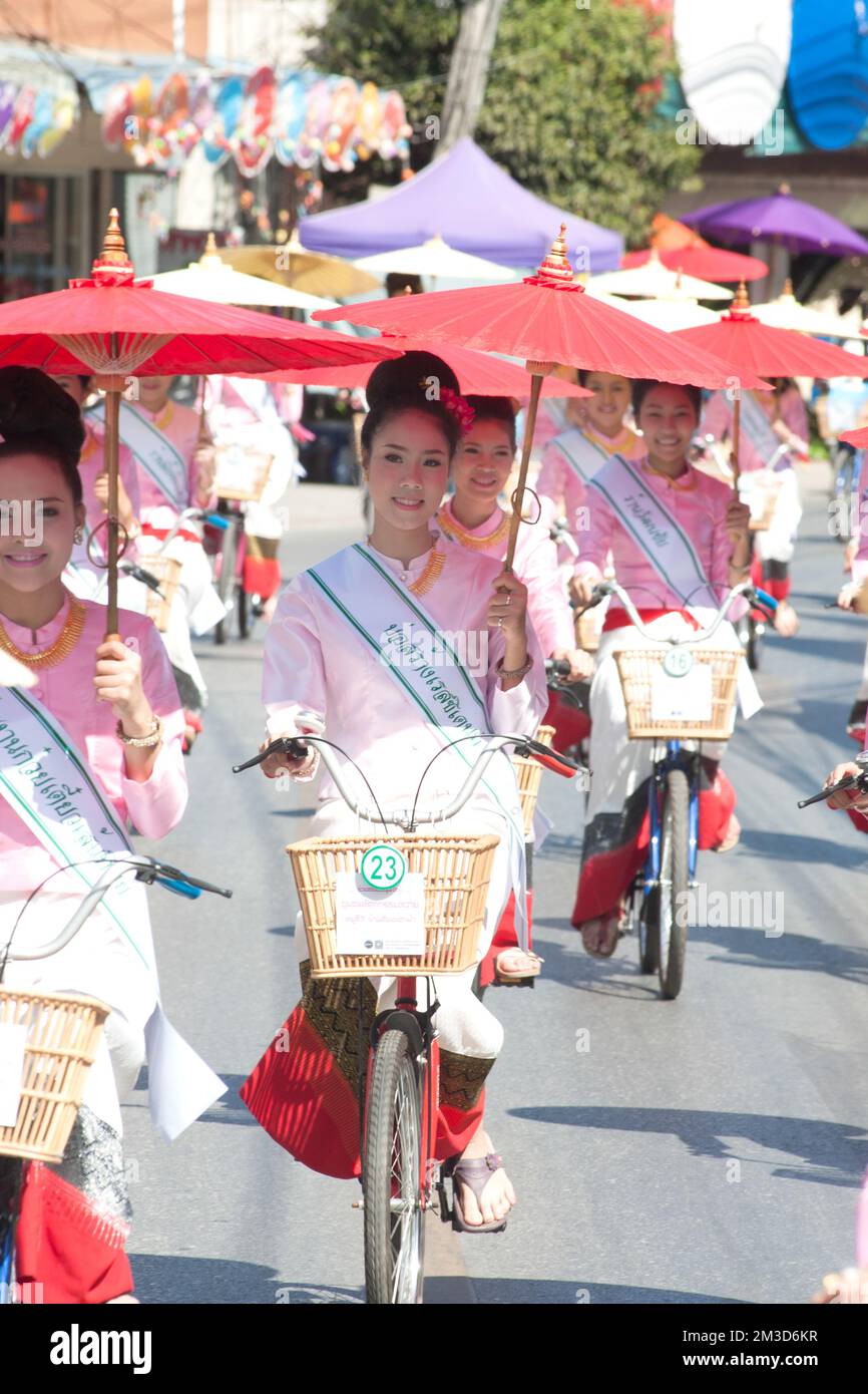 Gruppe von Frauen in traditionellen Kostümen halten Schirm und Fahrrad Parade Show beim 33.. Jubiläum des Bosang Regenschirmfestivals, San Kampaeng, Chiang Mai. Stockfoto