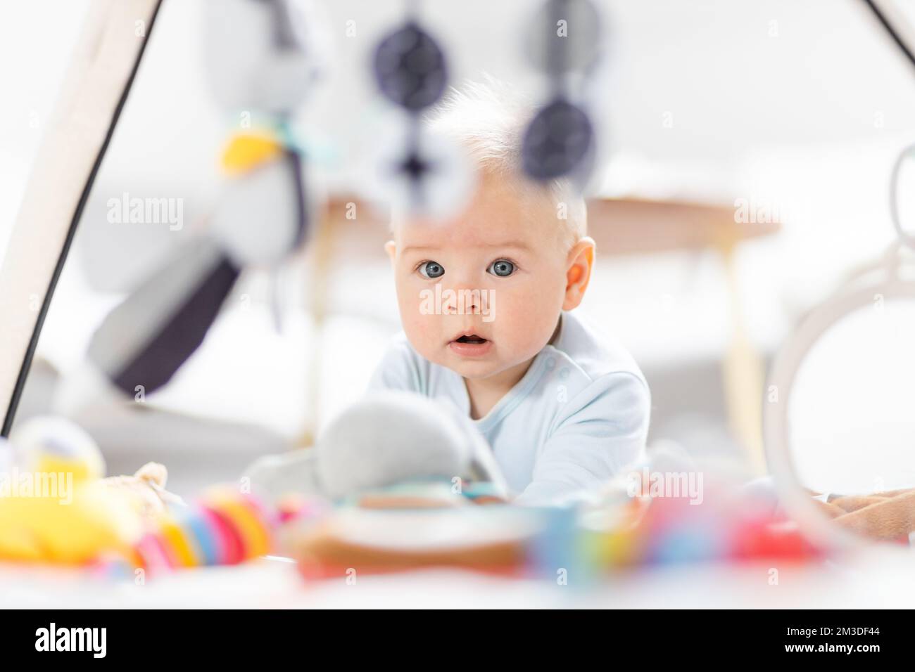 Niedlicher Baby Junge spielt mit hängendem Spielzeug Bogen auf Matte zu Hause Baby-Aktivität und Spielzentrum für die frühe Säuglingsentwicklung. Baby spielt zu Hause. Stockfoto