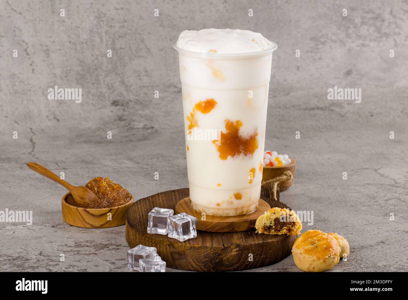 Boba- oder Tapiokapperlen ist taiwan Bubble Milk Tea in Plastikbecher mit Ananasmarmelade auf texturiertem Hintergrund, Sommererfrischung. Stockfoto