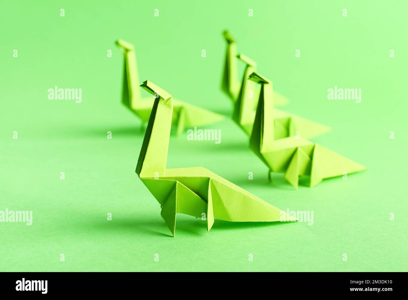 Origami-Dinosaurier auf grünem Hintergrund, Nahaufnahme Stockfoto