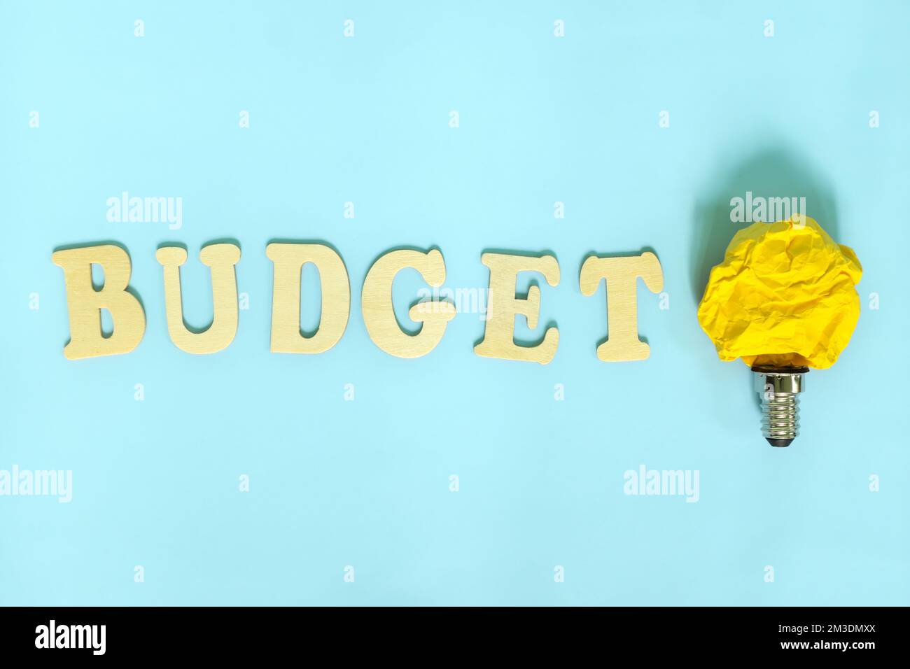 Konzept der Budgetierung und Budgetierung von Ideen und Tipps. Helle gelbe Glühlampe mit zerknittertem Papier. Stockfoto