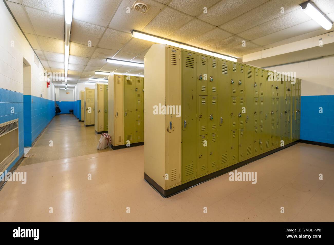 Unscheinbarer Umkleideraum mit altem gelb-grünen Metallraum, Fitnessraum, Schließfächer mit alter abgehängter Decke. Stockfoto