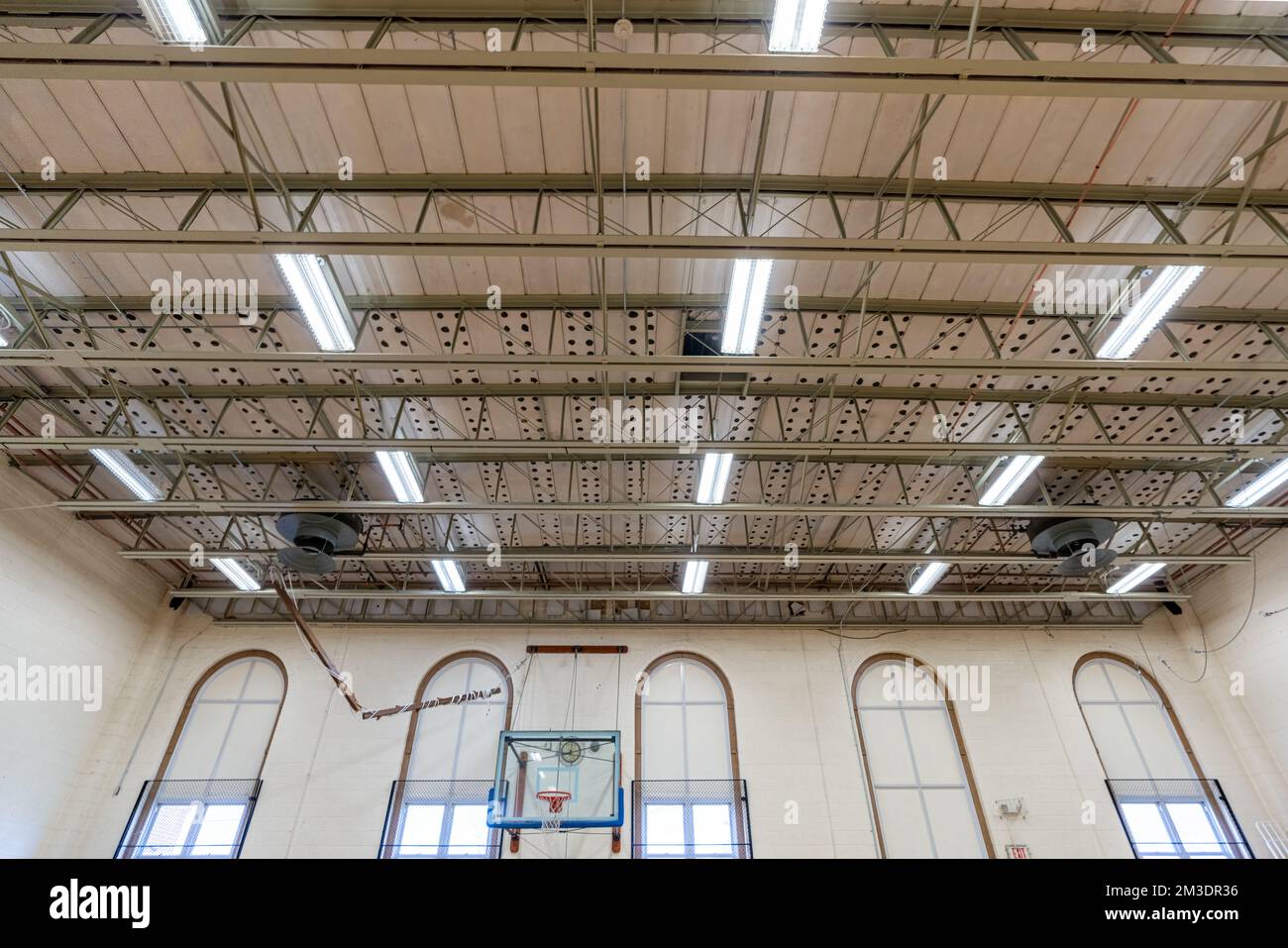 Decke eines unscheinbaren US-Gymnasiums mit tragenden Metalldächern und Leuchtstofflampen. Stockfoto