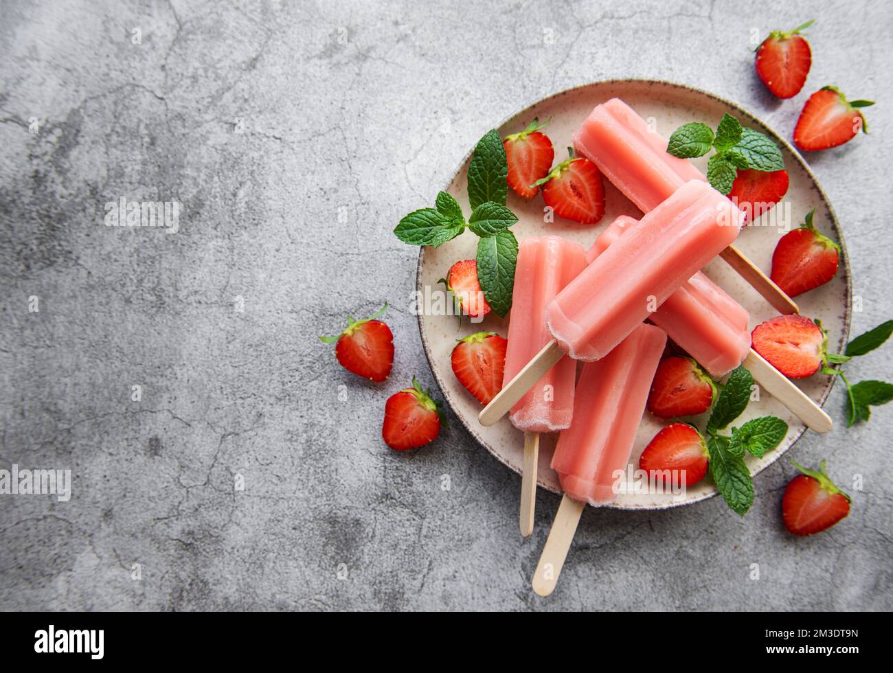 Hausgemachte gefrorene Erdbeer-Eis-Eiszapfen und frische Erdbeeren auf einem betonierten Hintergrund. Sommerdessert Stockfoto