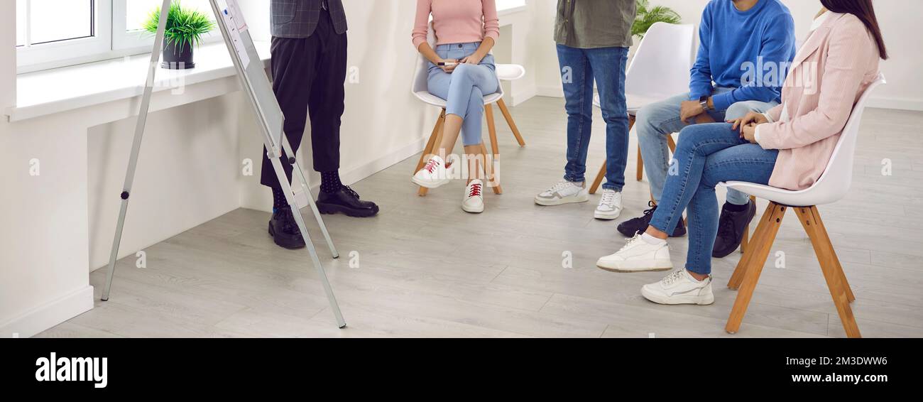 Junger Mann, der während der Besprechung des Geschäftsteams vor dem Whiteboard eine Präsentation hält Stockfoto