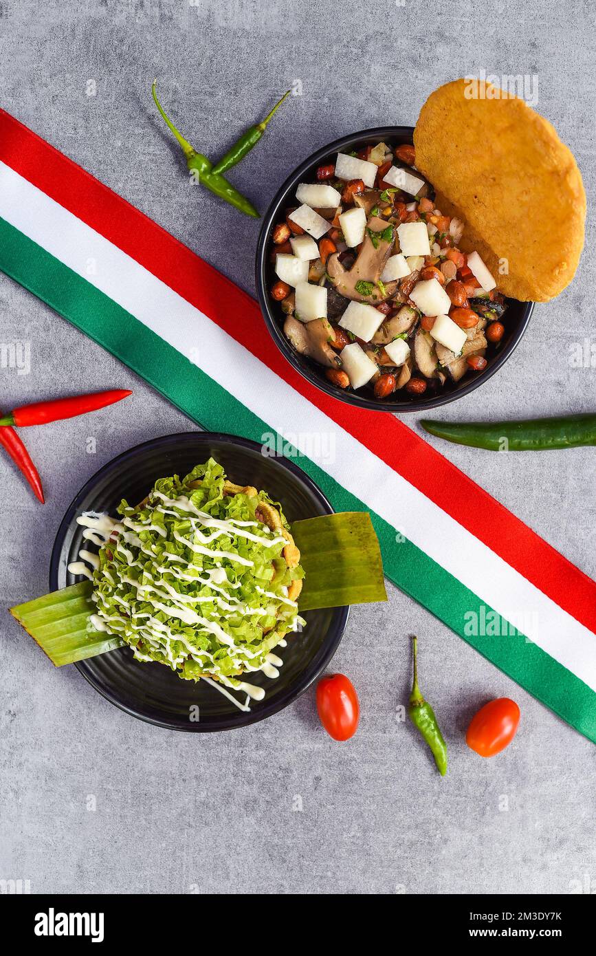 Mexikanische Gerichte von Rom und Coyoacan auf schwarzen Tellern mit Blick auf Kirschtomaten und Chili-Pfeffer Stockfoto