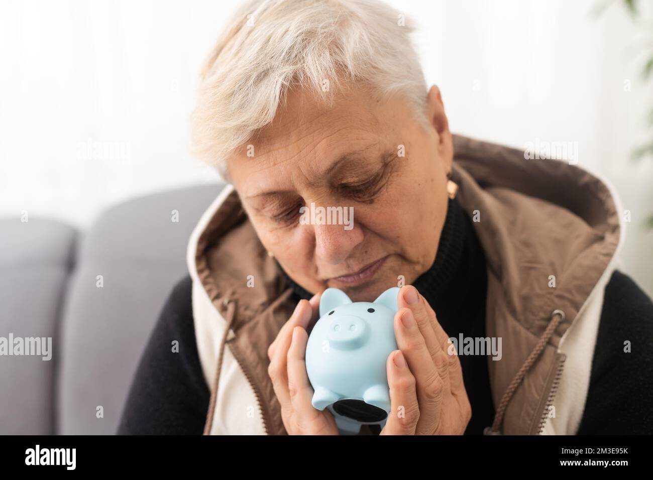 Geldverwaltungskonzept. Eine ältere Frau hält ein Sparschwein Stockfoto