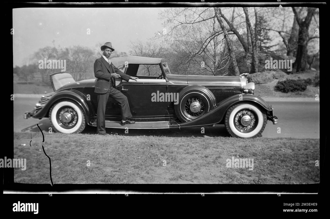 Ein Mann im Anzug steht vor einem Auto mit einer Zigarette, einem Cabriolet, einer Zigarette. Jack Miller Kollektion Stockfoto