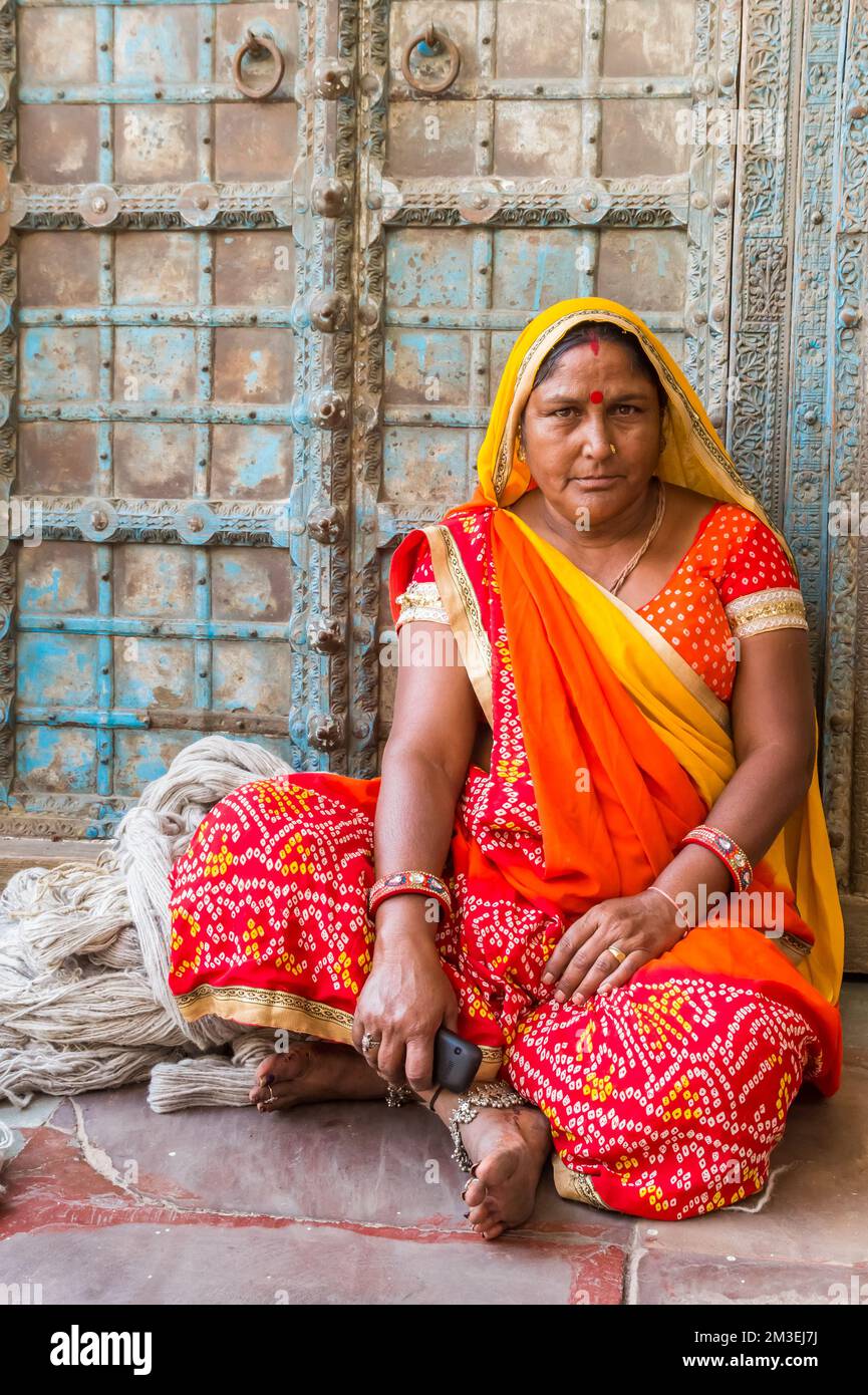 Porträt einer indianerin in bunter, traditioneller Kleidung, die an einer alten Tür sitzt Stockfoto