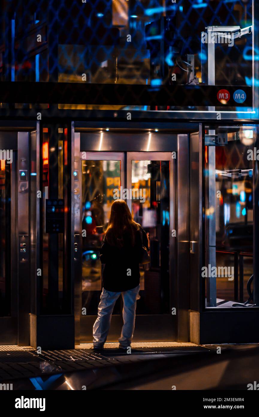 Ein senkrechter Hintern eines Mädchens, das auf eine Fahrt zu den U-Bahn-Linien wartet, mit dem Aufzug im Hintergrund Stockfoto