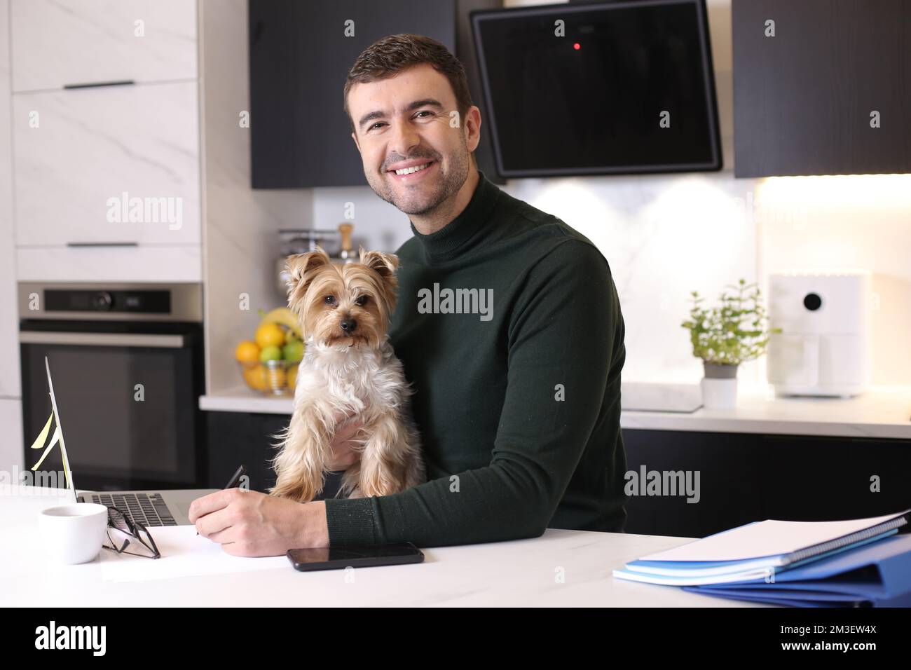 Attraktiver Mann, der von zu Hause aus mit seinem Schoßhund arbeitet Stockfoto