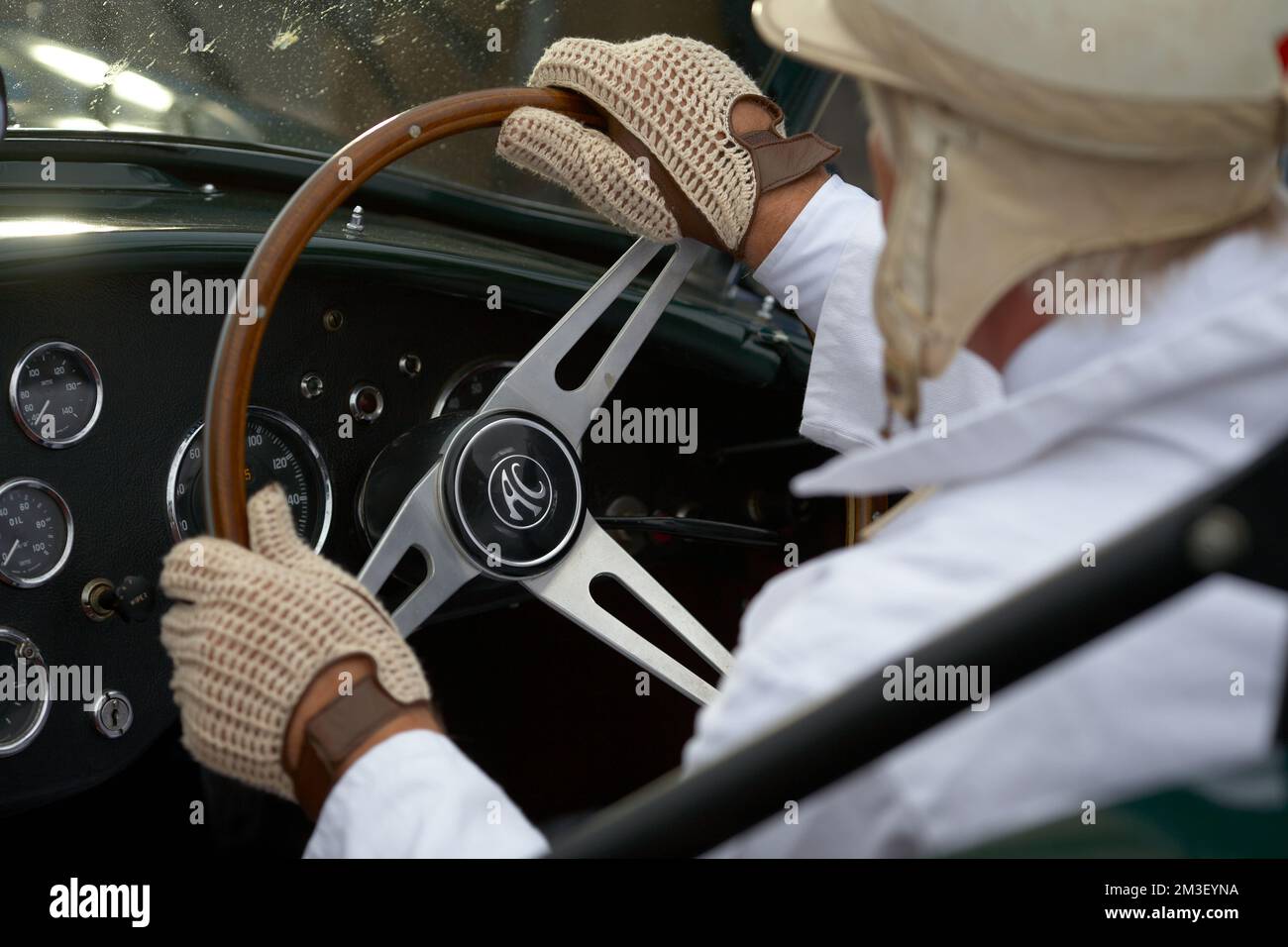 Hände am Lenkrad eines Autofahrers. Hände eines Mannes in klassischem englischem Leder Fahrhandschuhe im Oldtimer. Stockfoto